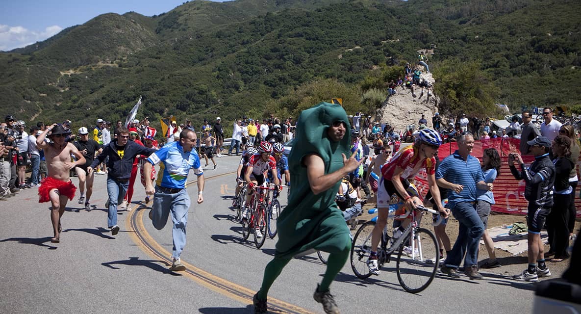 <p>The fans play a huge roll and appear in the middle of nowhere. They will sleep along the roadside and do whatever they can to get a glimpse as the bikers race past. Here some fans run uphill in custom as long as their legs will carry them.</p>
